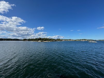Wide open water with low islands on the horizon under a blue sky, near Möja