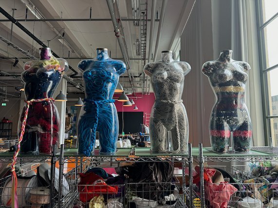 Four decorated mannequin torsos on a shelf in a textile workshop