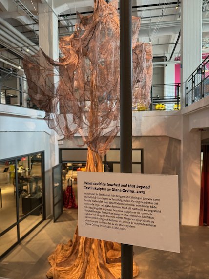 Hanging textile sculpture with an information sign in front