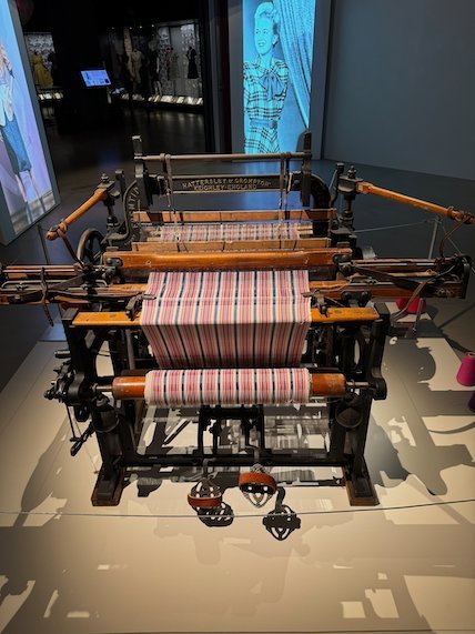 Old loom that weaves striped fabric, in a dark exhibition room