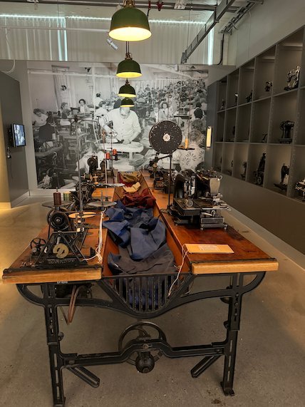 Workshop table with old sewing machines and a photo wall