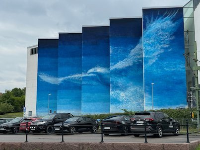 Blue sky mural on the facade of the Textile Museum, with cars in front