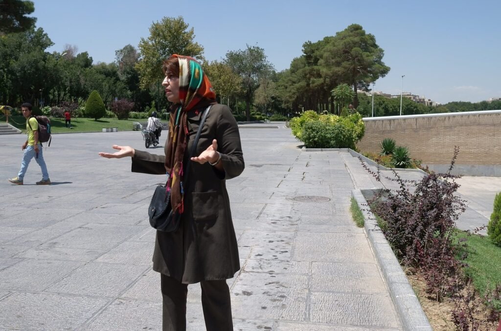 Woman in a scarf speaks to the group on a path by the river in Isfahan