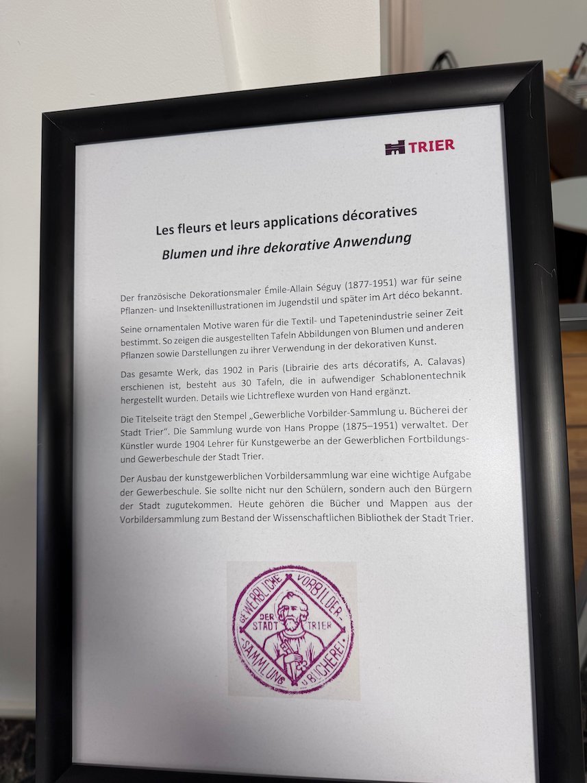 A framed text explains an exhibition of decorative flower prints in Trier.