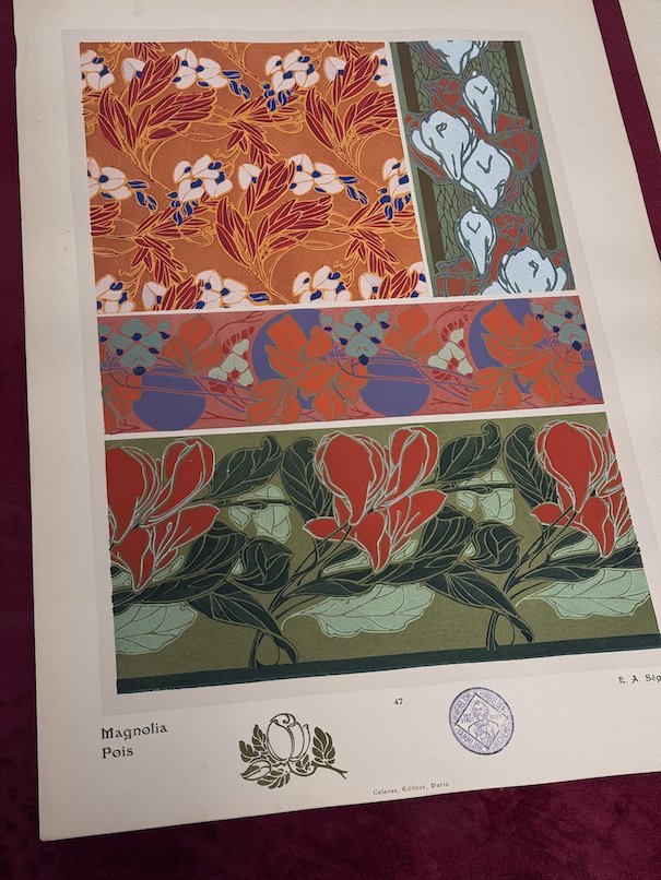 An Art Nouveau print with magnolia and red flower patterns hangs in Trier.