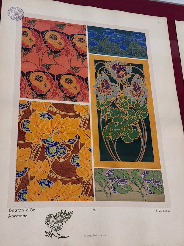 An Art Nouveau print with orange and blue flower patterns hangs in Trier.