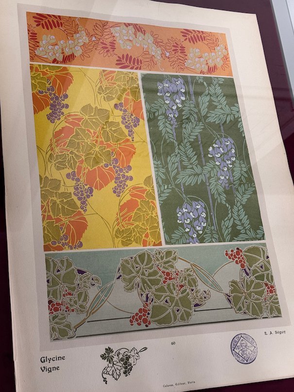 An Art Nouveau print with wisteria and vine patterns hangs in an exhibition in Trier.