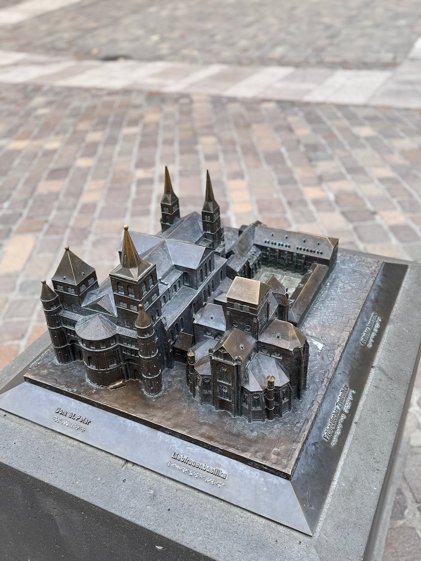 A bronze model of the cathedral buildings stands on a stone base in Trier.