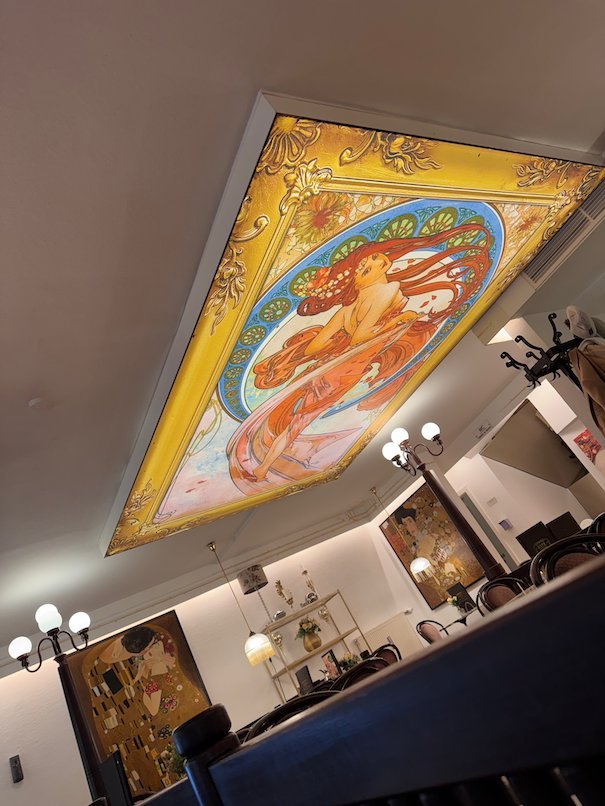 A painted glass ceiling in Art Nouveau style lights a cafe in Trier.