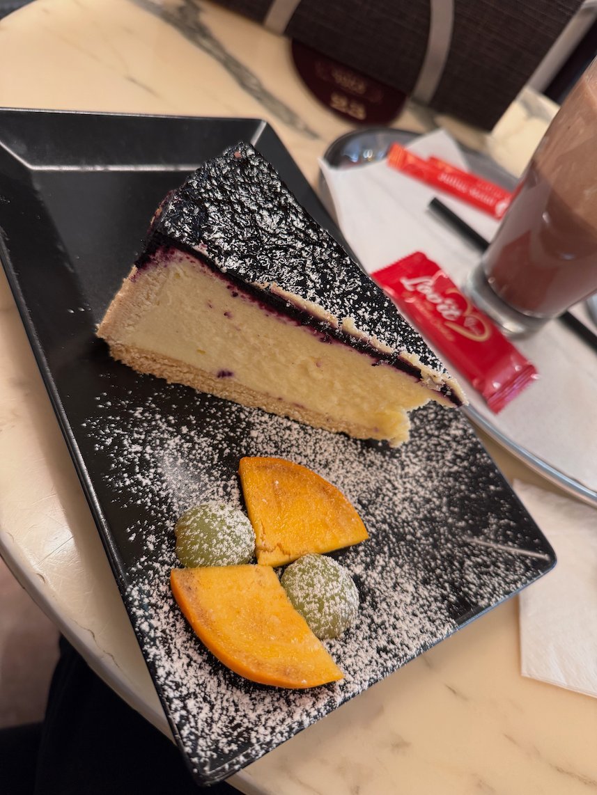 A slice of cheesecake with fruit lies on a black plate in a cafe in Trier.