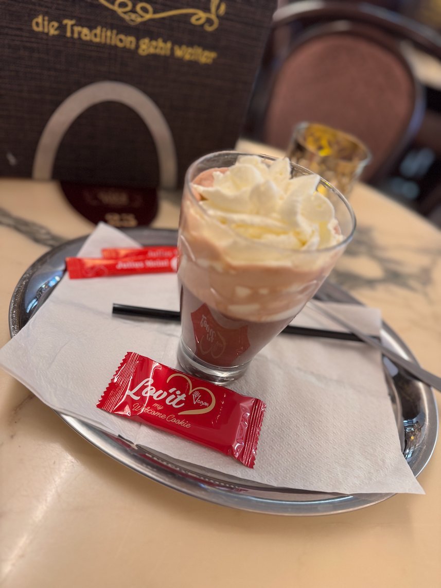 A hot chocolate with whipped cream stands on a marble table in a cafe in Trier.