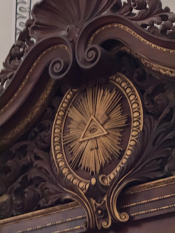 A carved wooden ornament with a golden eye symbol decorates furniture in Trier Cathedral.