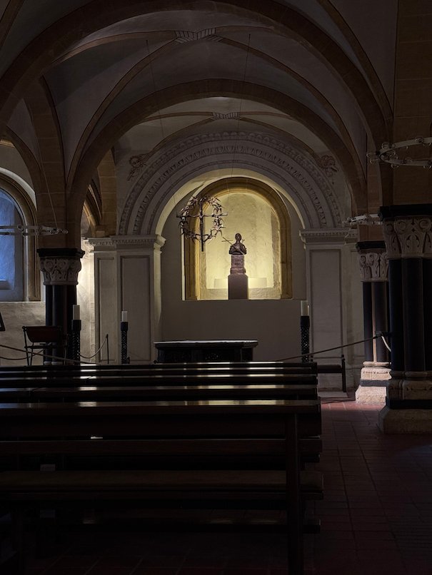 Pews face a lit statue niche in a vaulted chapel of Trier Cathedral.