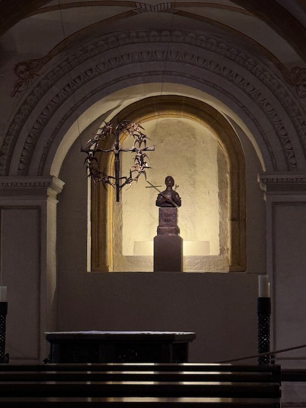 A statue stands in a lit niche in a quiet chapel of Trier Cathedral.