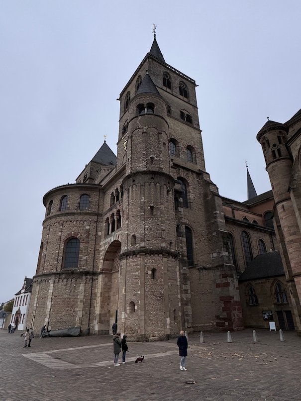 The Romanesque tower and walls of Trier Cathedral rise above the square.