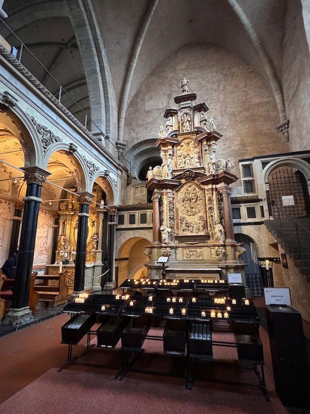 Candles burn in front of a carved side altar in Trier Cathedral.
