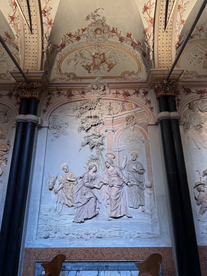 A white stucco relief with figures decorates a chapel wall in Trier Cathedral.