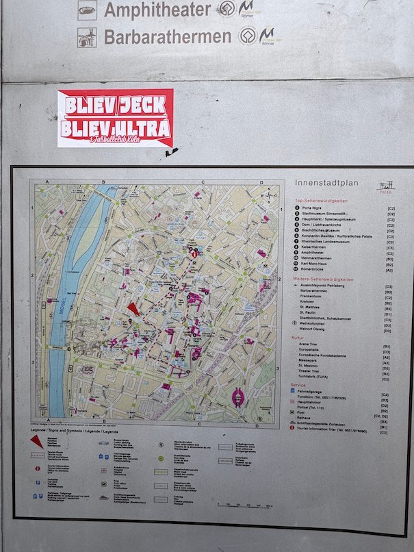 A city map with sights and a sign to the amphitheatre hangs on a wall in Trier.
