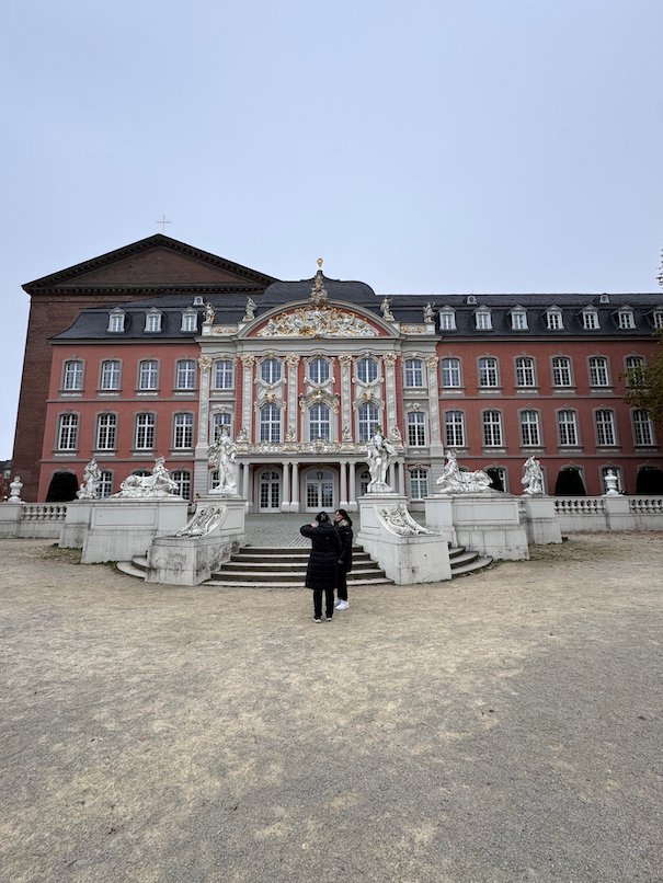 The pink facade of the Electoral Palace stands behind a square in Trier.
