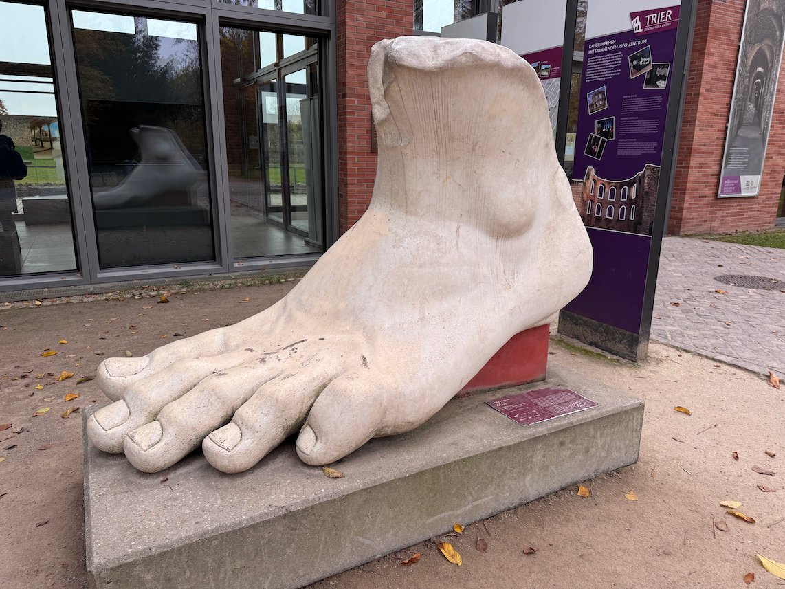 A large white sculpture of a foot stands outside a building in Trier.