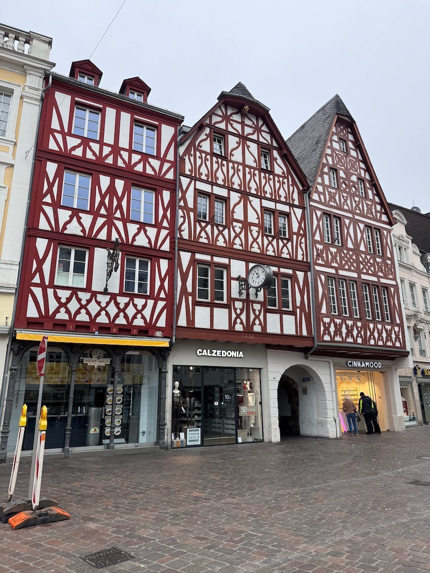 Red half-timbered houses with shops stand on the Hauptmarkt in Trier.