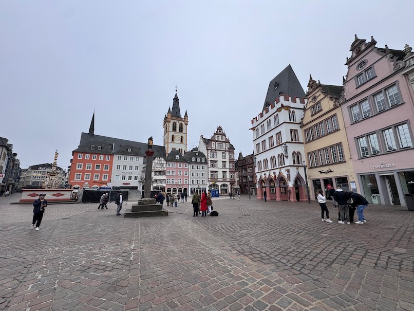 People walk around the market cross on the Hauptmarkt in Trier.