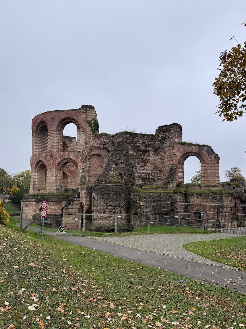 The Roman walls of the Imperial Baths stand on a green lawn in Trier.