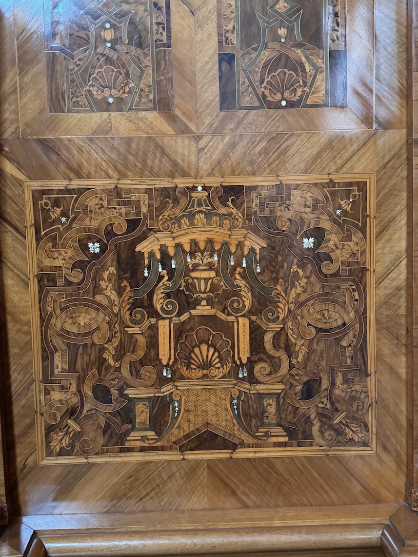 An old wooden cabinet panel has inlaid designs of buildings in Trier.