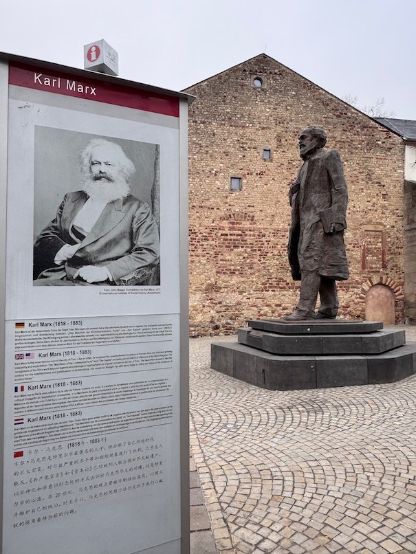 An information pillar about Karl Marx stands in front of his bronze statue in Trier.