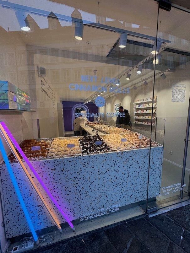 A modern pastry shop with a speckled counter and neon light is in Trier.