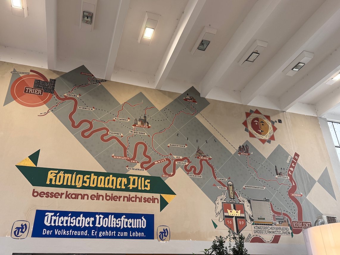 A wall mural shows a map of the Moselle with beer adverts in Trier.