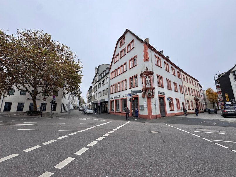 A red and white house stands on a quiet street corner in the old town of Trier.