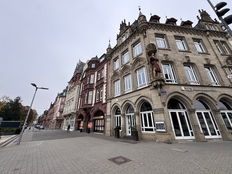 Ornate sandstone buildings with statues line a street in Trier.