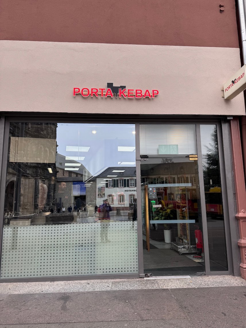 The front of a small kebab shop named Porta Kebab stands near the Porta Nigra.