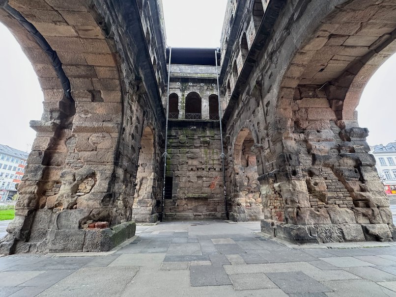 Huge stone arches frame the inner courtyard of the Porta Nigra in Trier.