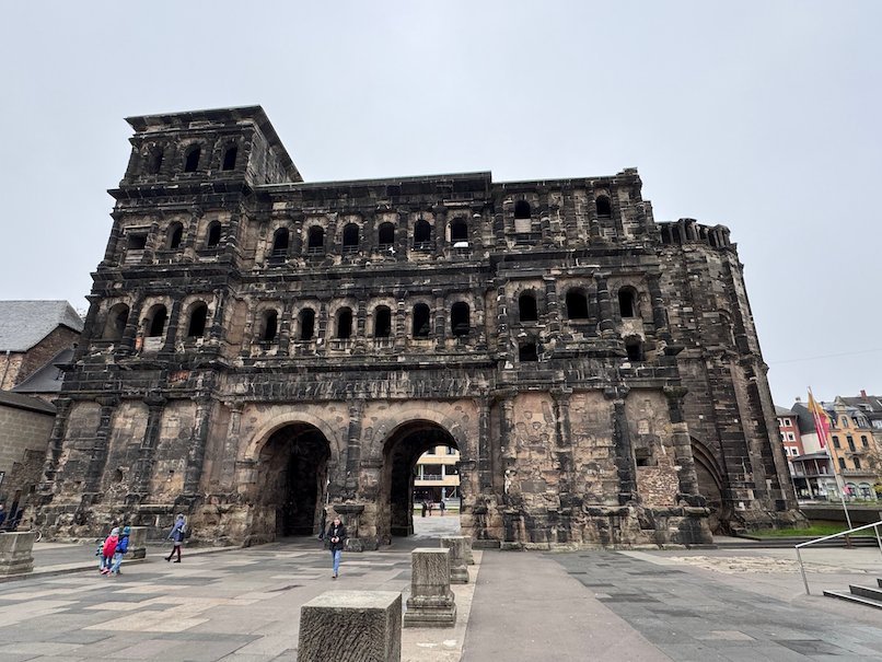 The Porta Nigra with its two arched gates stands under a grey sky in Trier.