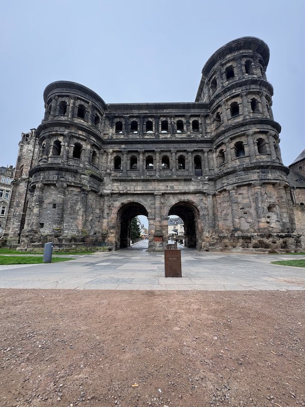 The dark Roman city gate Porta Nigra stands on a square in Trier.