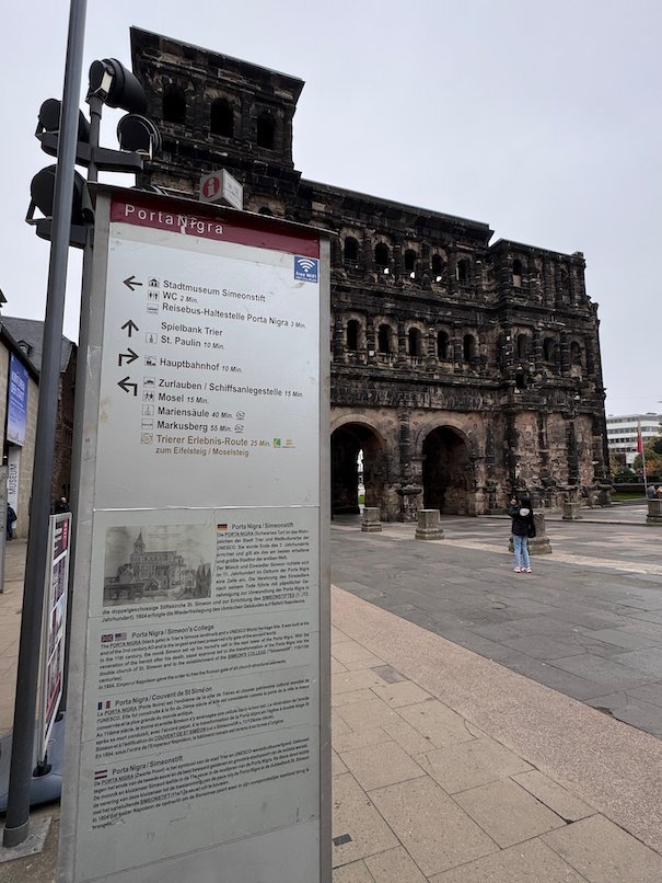 A signpost with directions stands in front of the Porta Nigra in Trier.