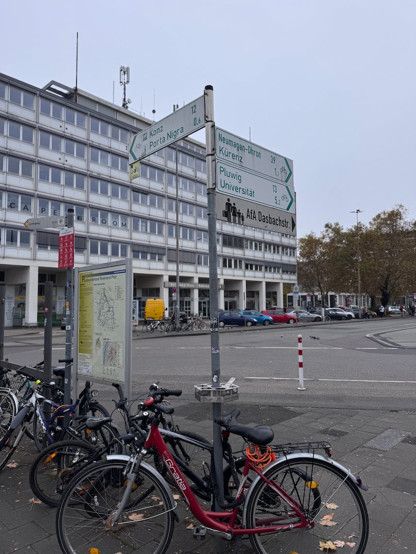 Signposts and parked bicycles stand on a street in Trier.