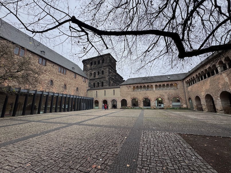 Arcades surround a quiet cobbled courtyard next to the Porta Nigra in Trier.