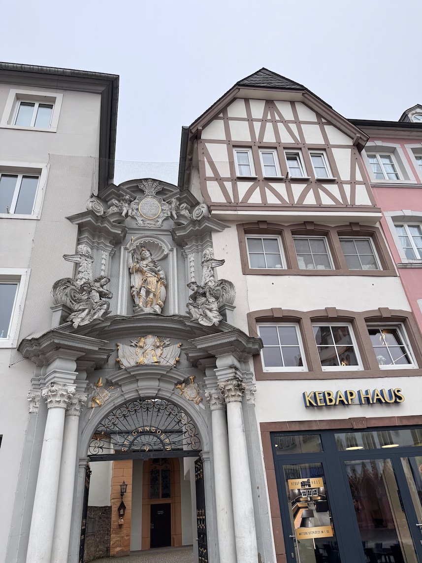 A white baroque portal leads from the Hauptmarkt to St. Gangolf church in Trier.