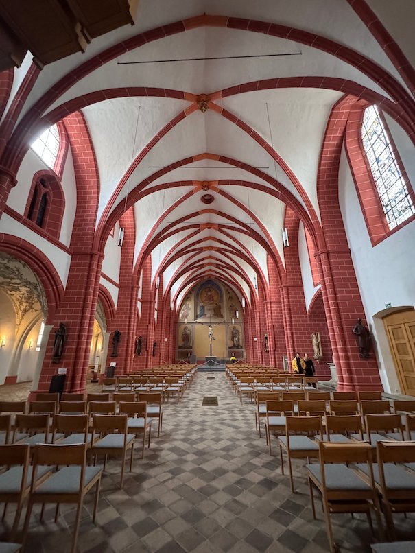 Red painted ribs cross the white vault of the nave of St. Gangolf in Trier.