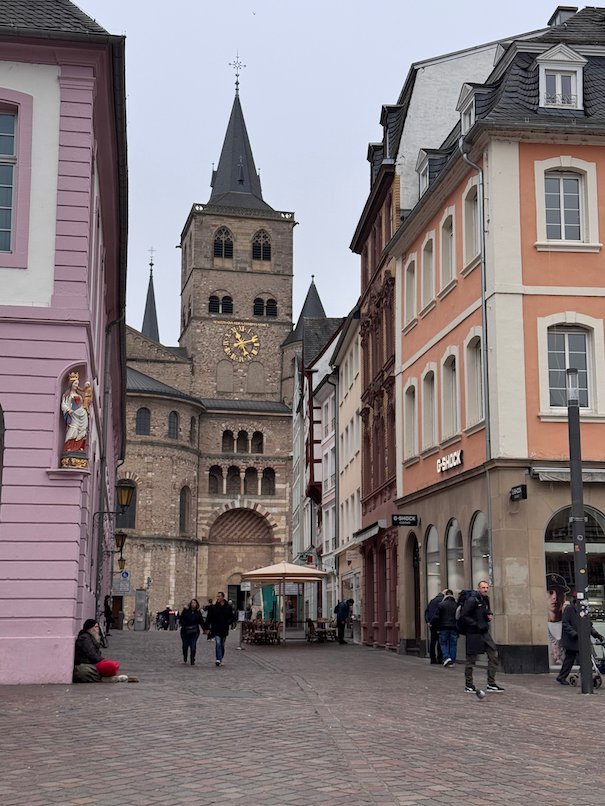 A street with colorful houses leads to the tower of Trier Cathedral.