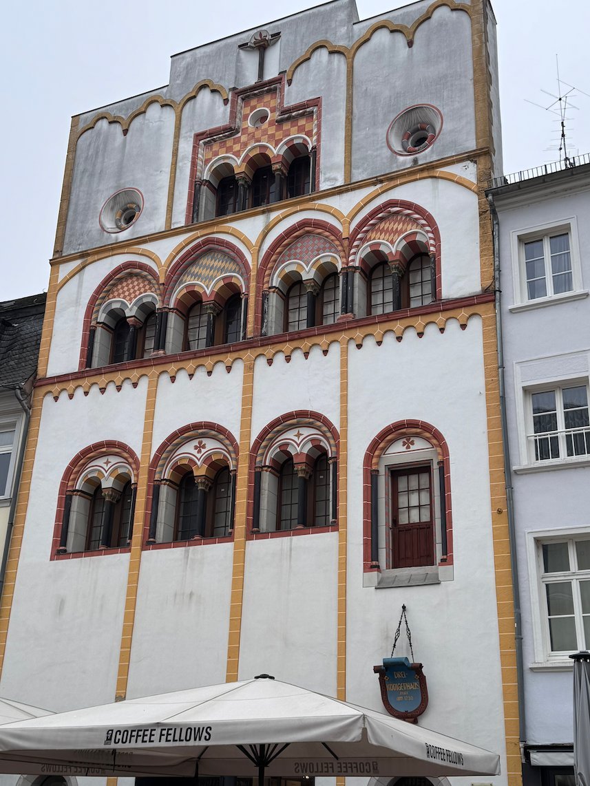 The white Three Kings House with red arched windows stands on Simeonstrasse in Trier.