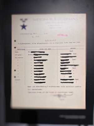 Old typed document with black redacted lines, in a museum display