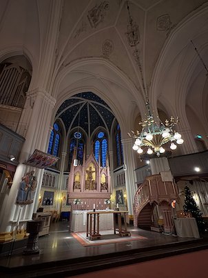Altar and stained glass windows inside Umeå City Church, with a chandelier