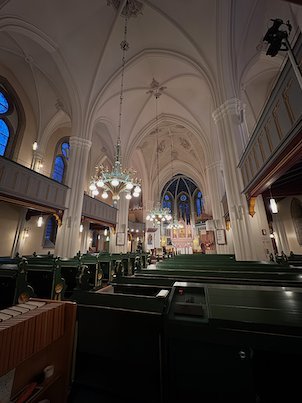 Nave of Umeå City Church with green pews, white vaults and blue windows