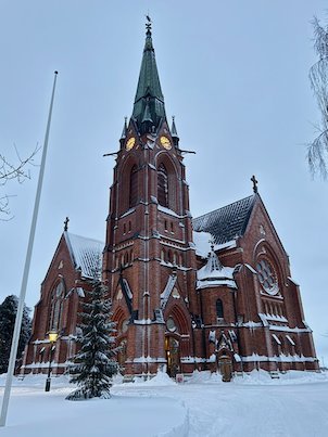 Umeå City Church with its green spire and red brick walls on a snowy winter day