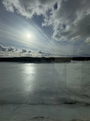 Frozen Ume River under dramatic clouds, with the low sun reflected in the ice