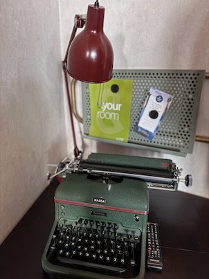 Old green typewriter and a red desk lamp on a hotel desk